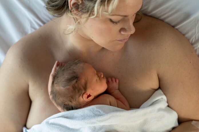 Mutter hält ihr Neugeborenes in ruhiger Umgebung nach der Geburt – Symbol für Erholung und sanfte Pflege im Wochenbett