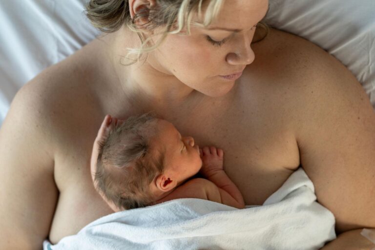 Mutter hält ihr Neugeborenes in ruhiger Umgebung nach der Geburt – Symbol für Erholung und sanfte Pflege im Wochenbett